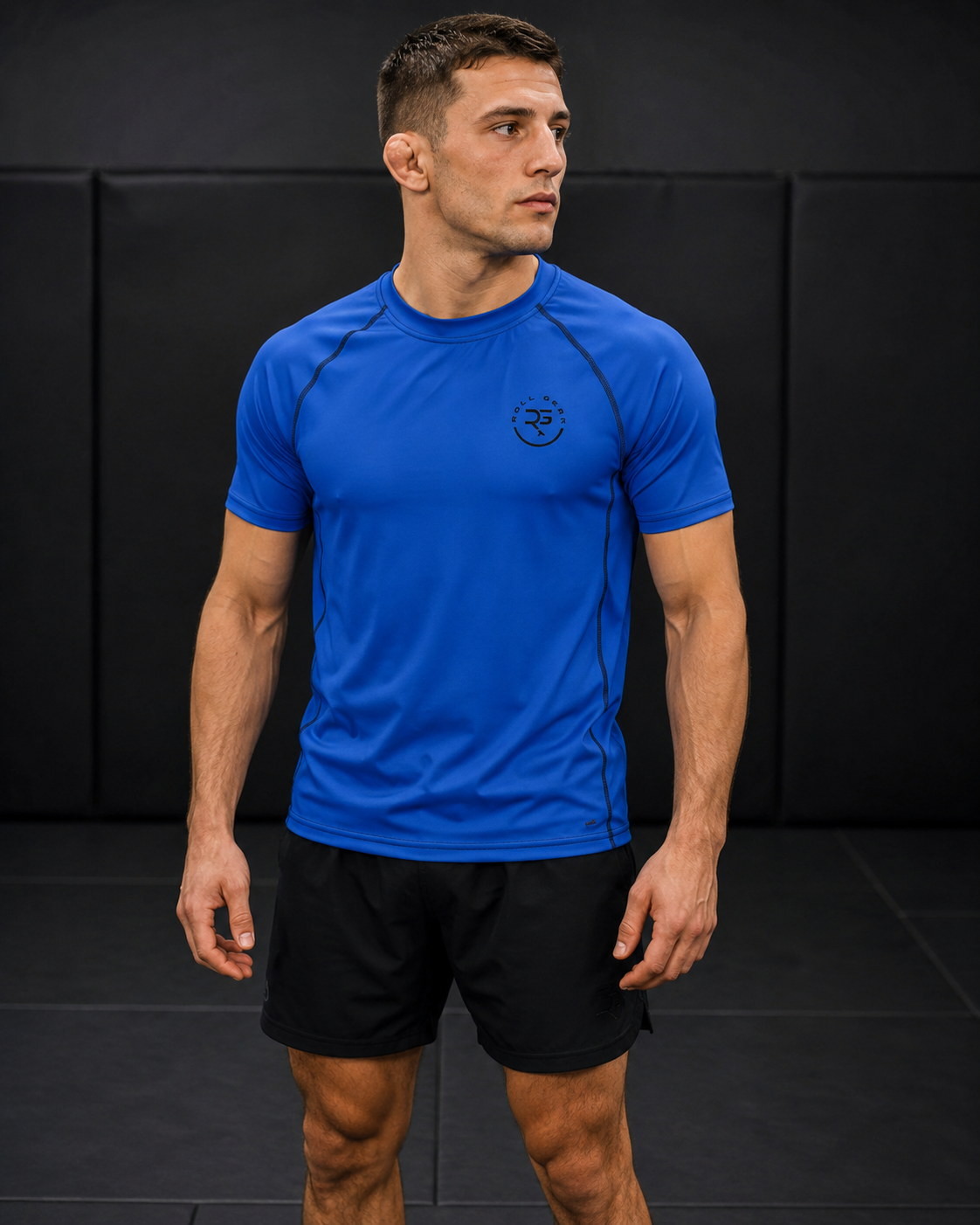 Man wearing a blue athletic shirt and black shorts against a black background