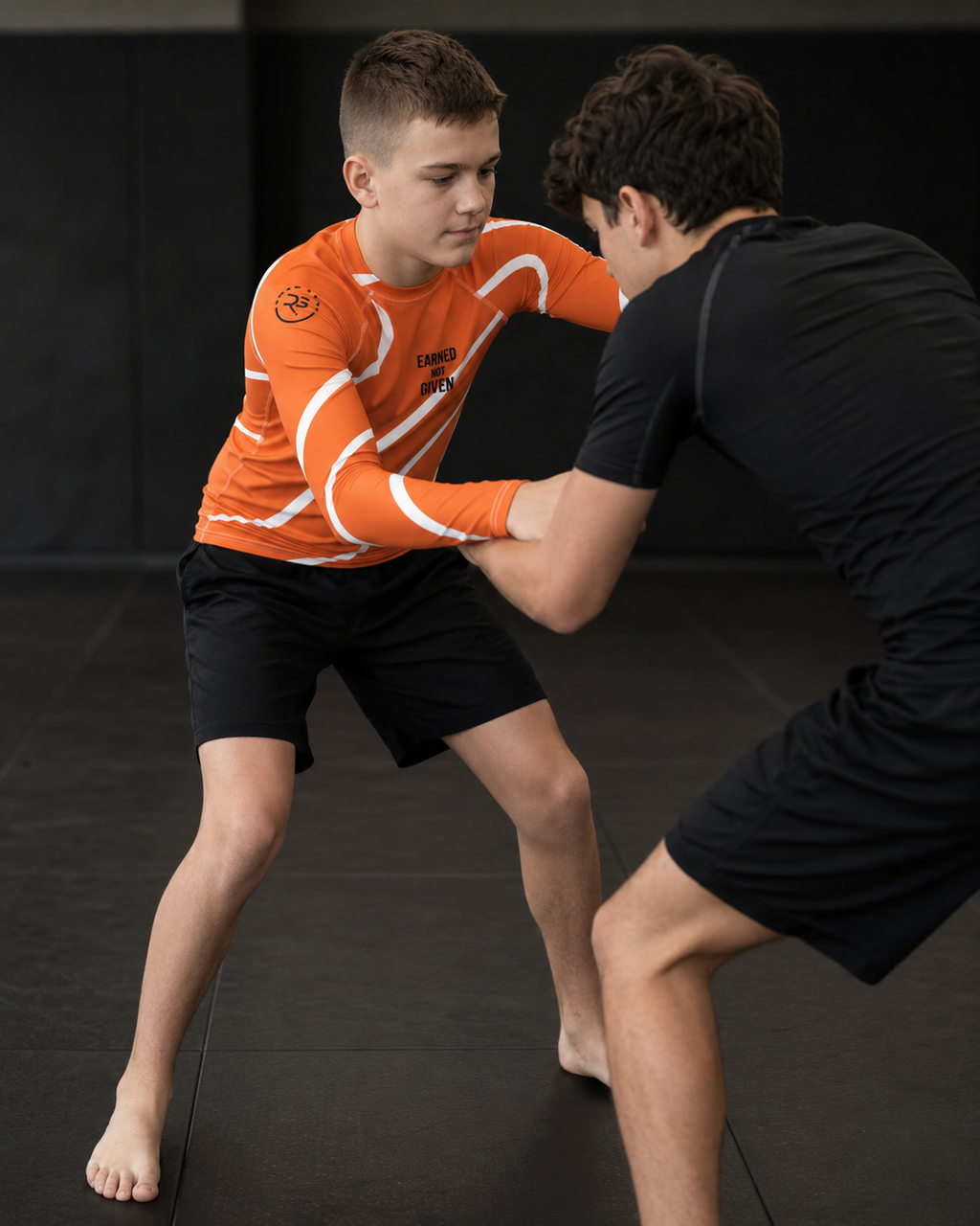 Two individuals practicing martial arts on a dark mat.