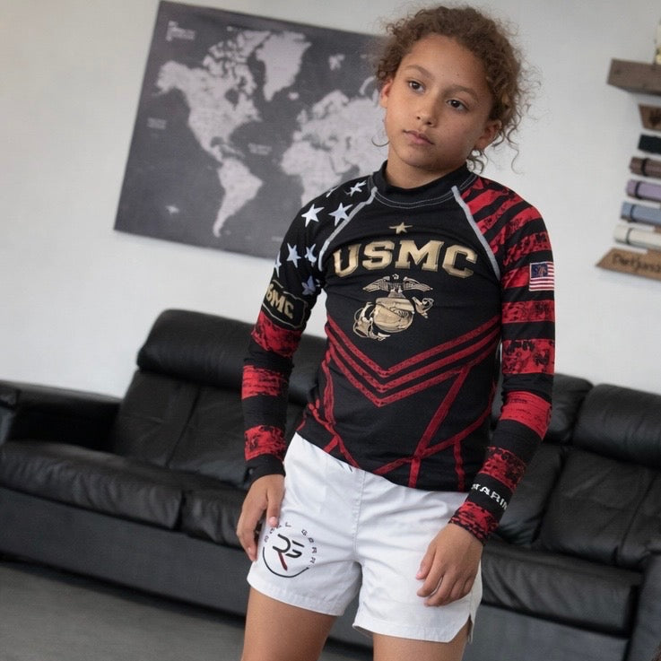Child wearing a USMC-themed shirt in a living room setting