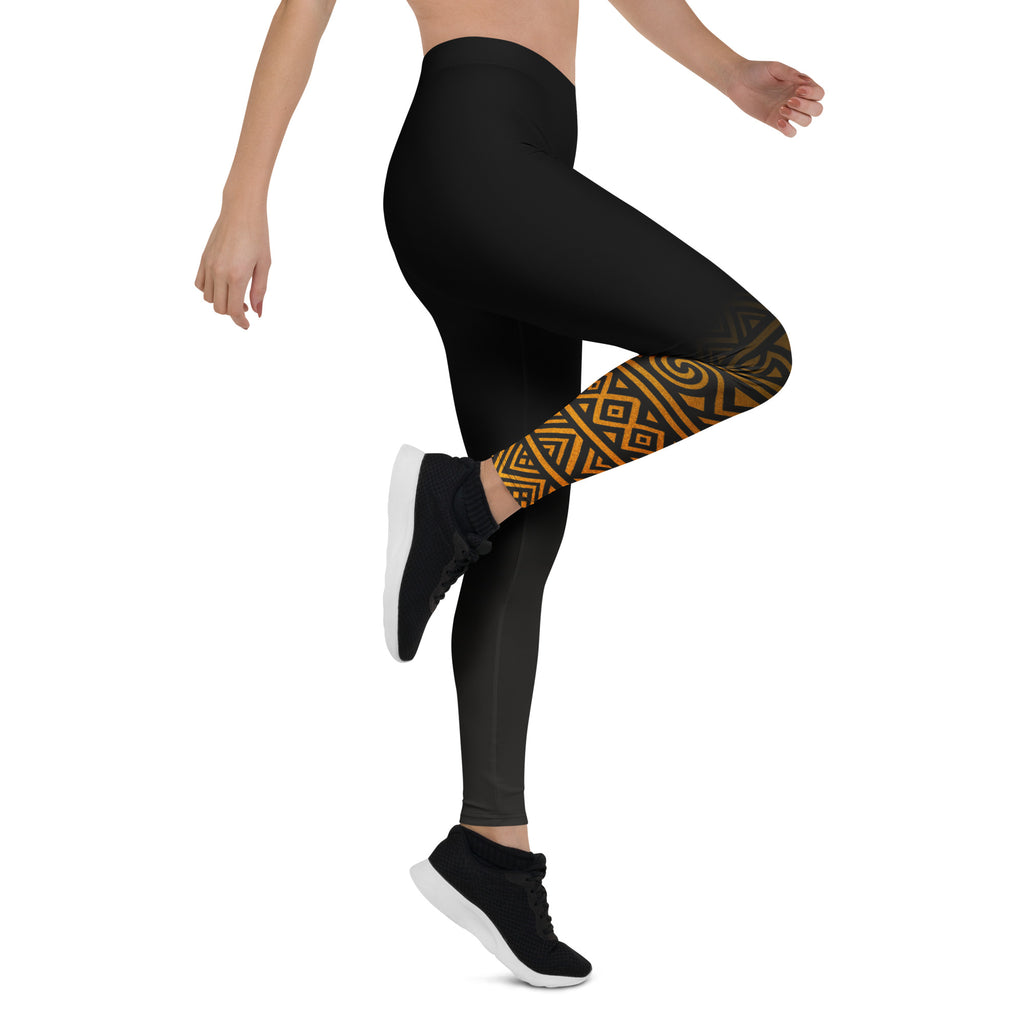 Black leggings with a gold geometric pattern on one leg, worn by a person on a white background