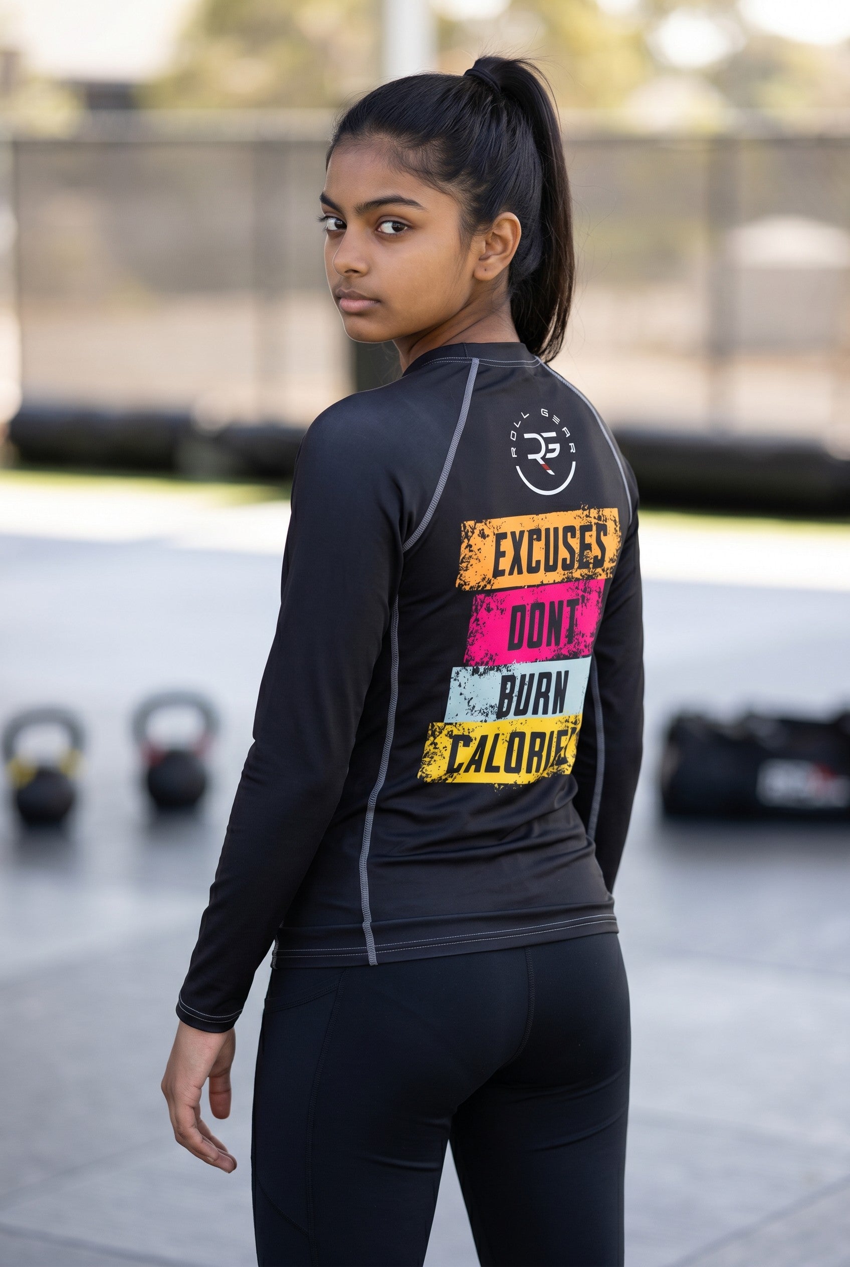 Person wearing a black athletic outfit with motivational text on the back, standing in an outdoor setting.