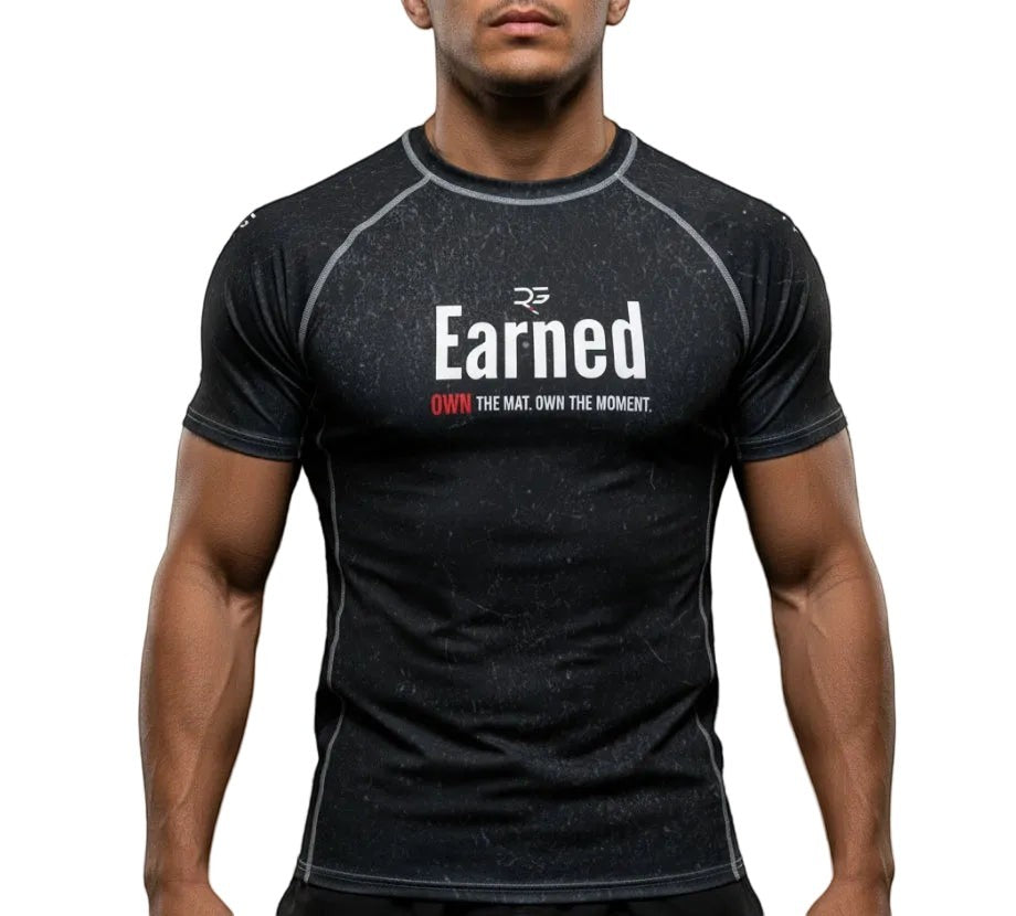 Roll Gear black short sleeve rash guard with "Earned" graphic print. Moisture-wicking, 4-way stretch fabric for BJJ, wrestling, and MMA.