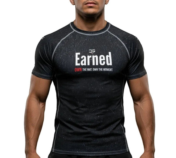 Roll Gear black short sleeve rash guard with "Earned" graphic print. Moisture-wicking, 4-way stretch fabric for BJJ, wrestling, and MMA.