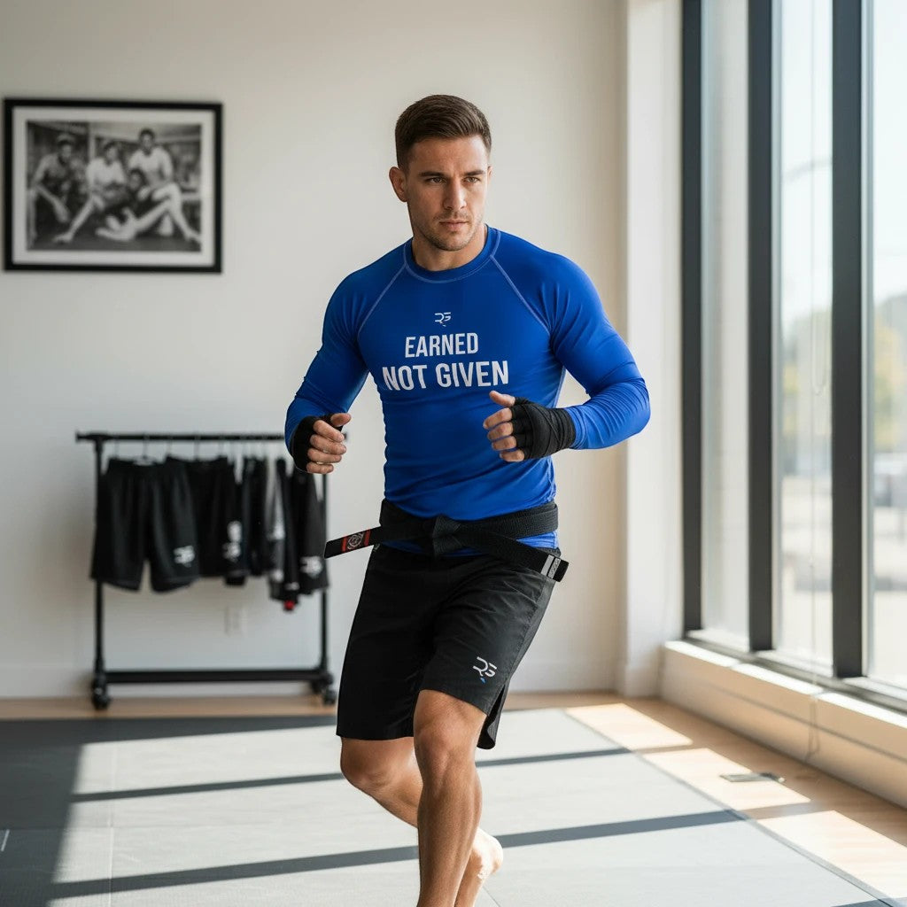 Roll Gear blue long sleeve rash guard with "Earned Not Given" graphic on chest, designed for training.
