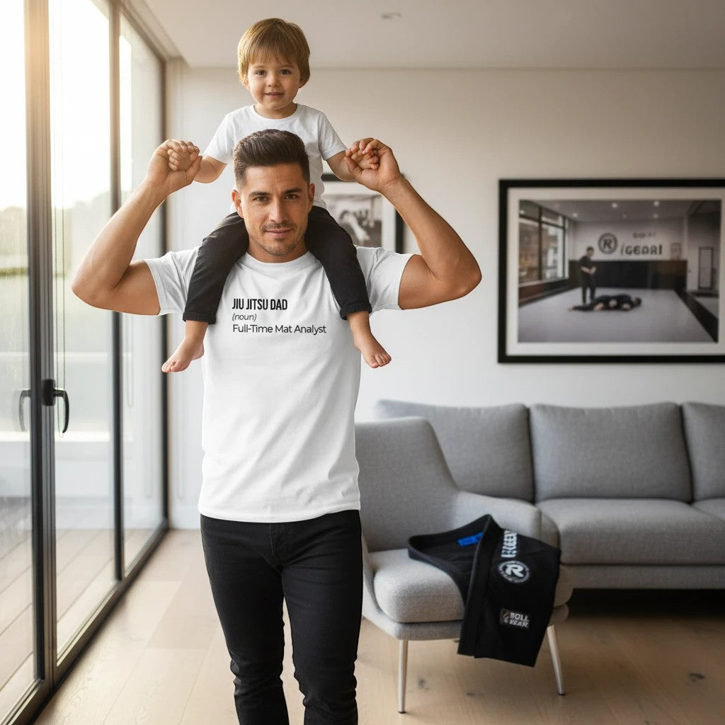Roll Gear white 100% cotton heavyweight t-shirt with "JIU JITSU DAD (noun) Full-Time Mat Analyst" graphic, worn by a man with a child on his shoulders.