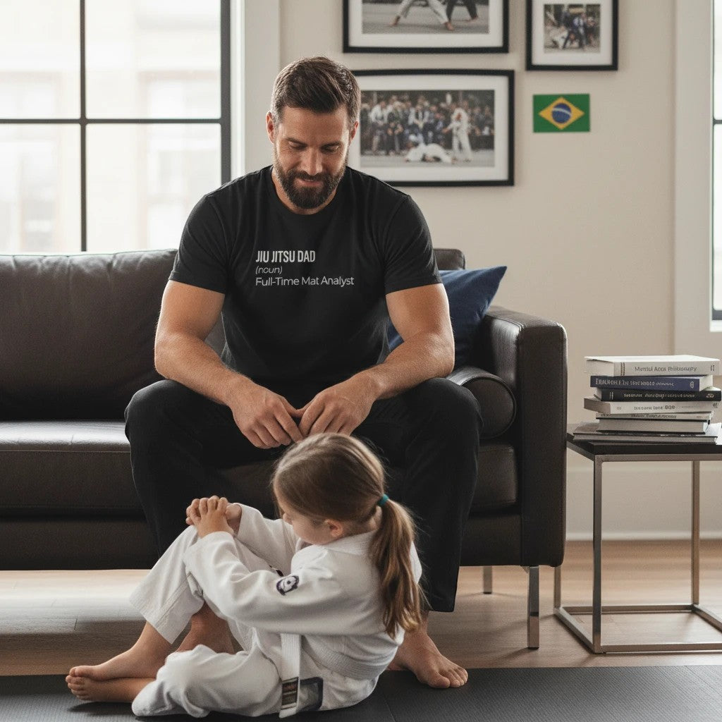 Roll Gear black 100% cotton heavyweight tee with "Jiu Jitsu Dad (noun) Full-Time Mat Analyst" graphic on front.
