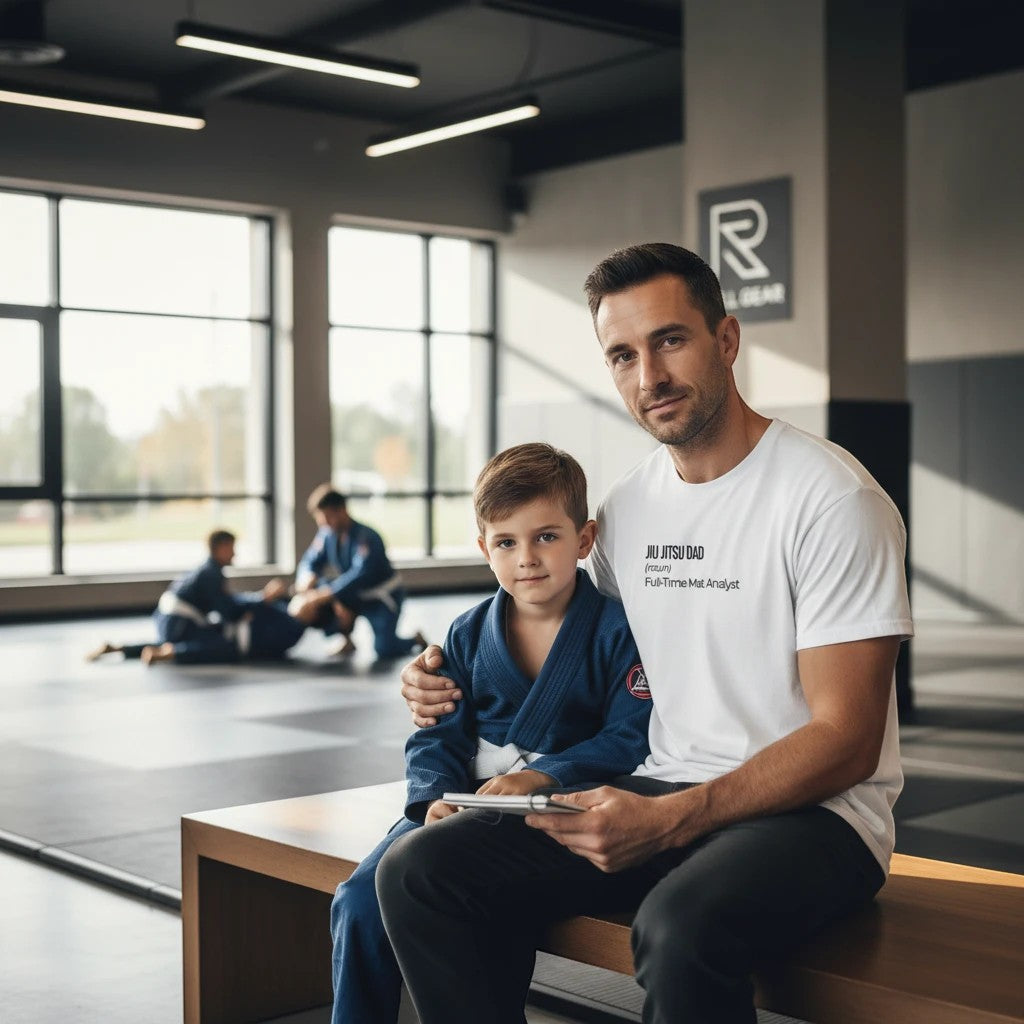 Roll Gear white cotton t-shirt with "Jiu Jitsu Dad (noun) Full-Time Mat Analyst" graphic on front. Man and child in jiu jitsu gi.