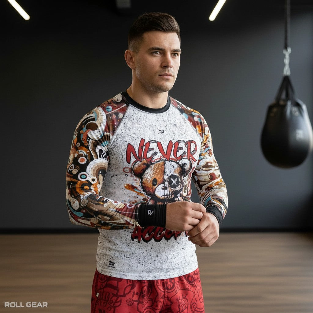 Roll Gear men's long sleeve rash guard with a graphic print of a split teddy bear and "Never Accept" text. White with colorful sleeves.