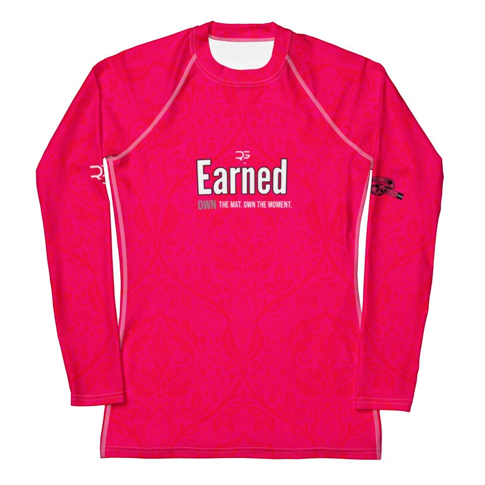 Roll Gear women's long sleeve rash guard in bright pink with a subtle pattern and "Earned" graphic. Designed for BJJ and grappling.