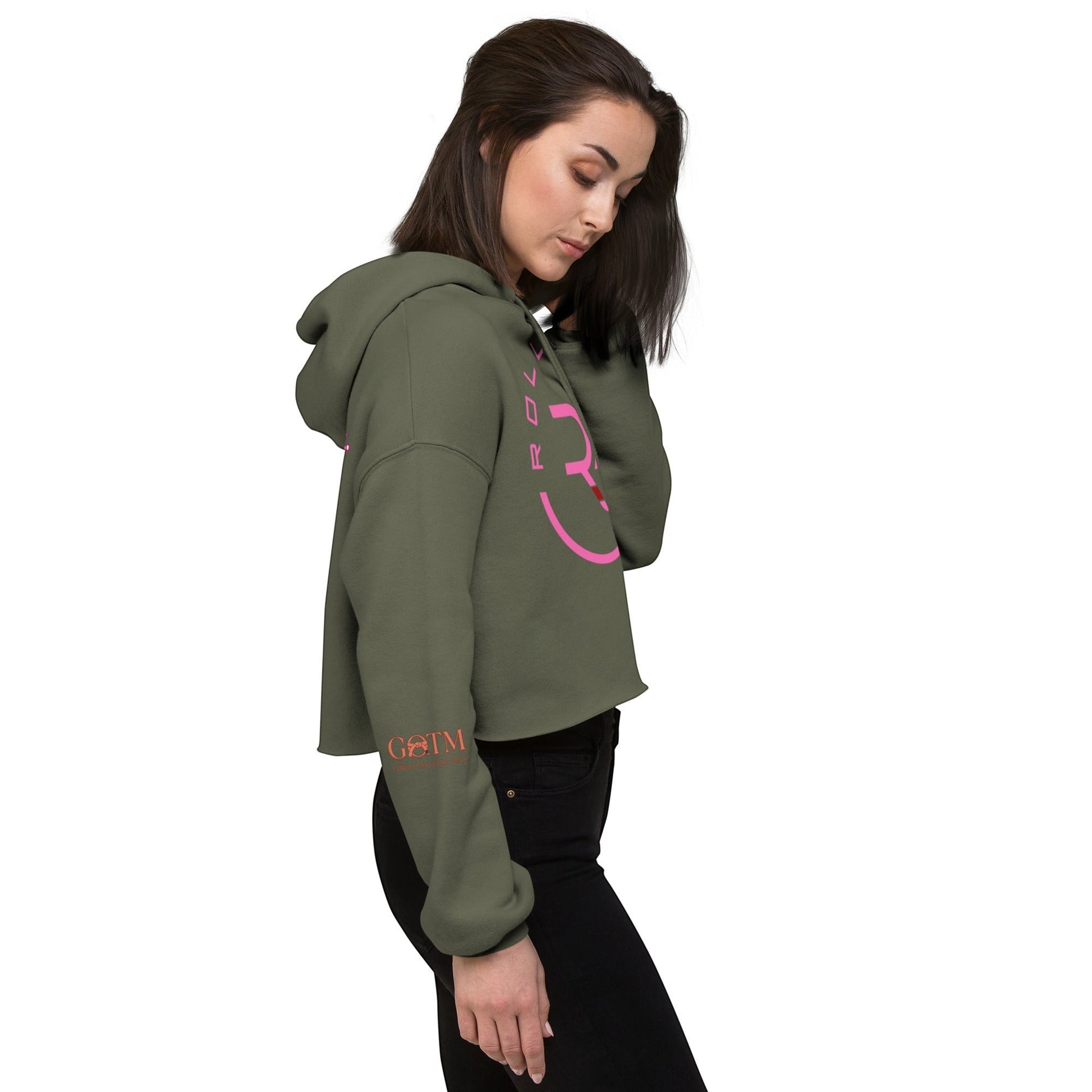 Roll Gear women's cropped olive green hoodie with pink logo on chest and sleeve detail. Model wears black jeans.