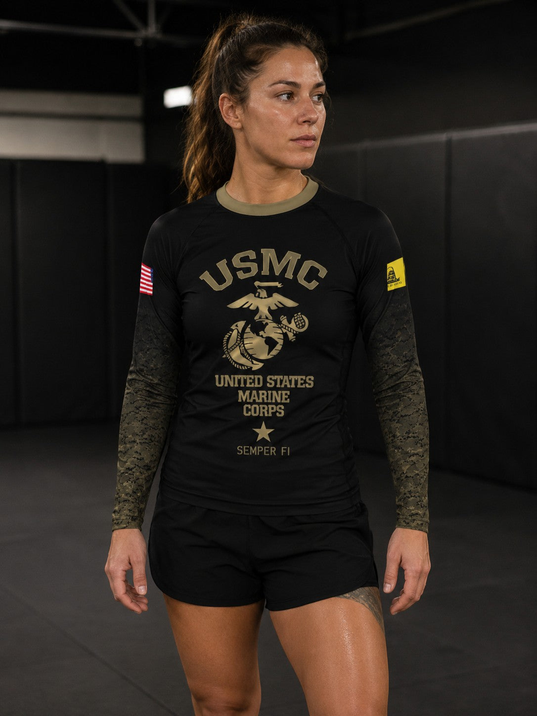 Roll Gear Women’s Marines Gold military rash guard in black with faded gold sleeves and USMC emblem. Compression fit, long sleeve.