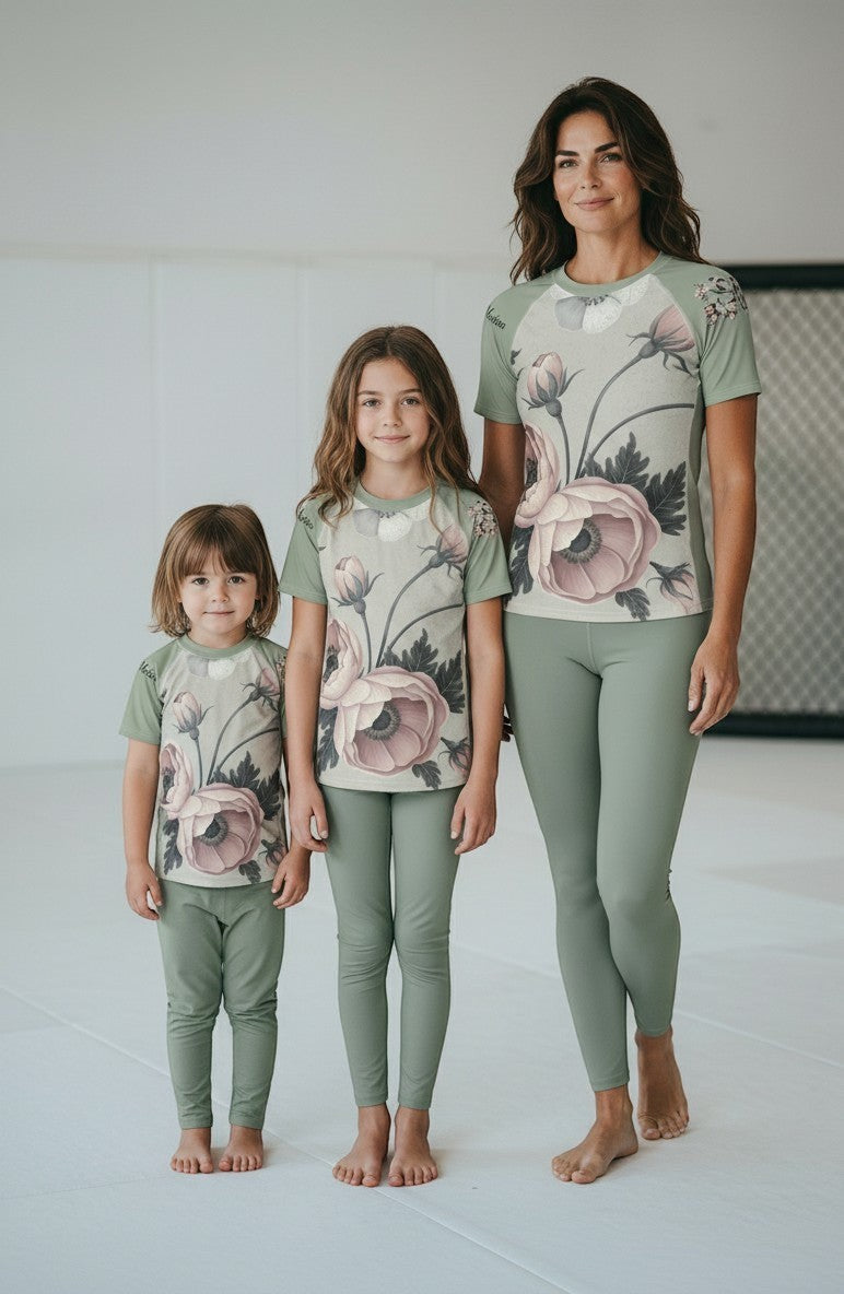 Roll Gear Always Blooming Rash Guard in sage green with a floral print, short sleeves, worn by a woman and two children.
